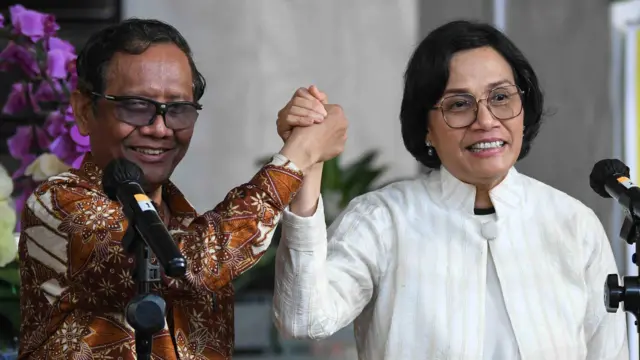 Menko Polhukam Mahfud MD (kiri) dan Menkeu Sri Mulyani (kanan) berjabat tangan usai menyampaikan keterangan di Kantor Kemenkeu, Jakarta, Sabtu (11/03). 