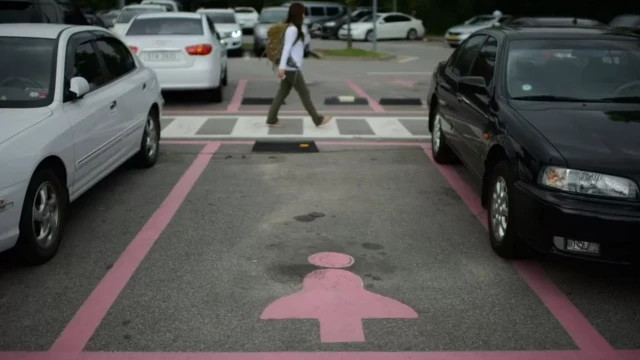 Foto colorida mostra simbolo de boneco com saia pintado de rosa em uma vaga