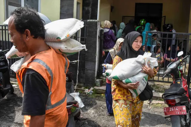 Keluarga Penerima Manfaat (KPM) membawa bantuan pangan beras sebanyak 20 kilogram di Kantor Kelurahan Nagarawangi, Kota Tasikmalaya, Jawa Barat,.