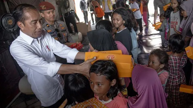 Presiden Joko Widodo (kiri) membagikan makanan untuk berbuka puasa kepada anak-anak pengungsi banjir Demak di Demak, Jawa Tengah, Jumat (22/3/2024).