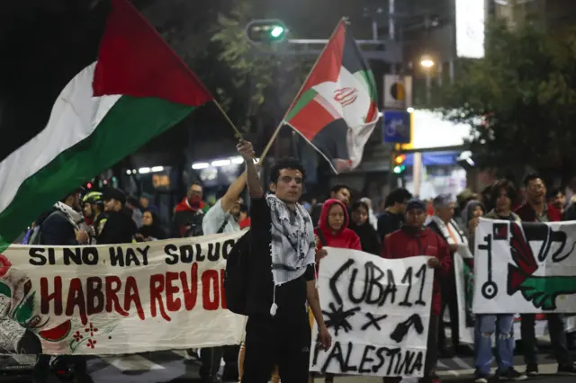 Manifestantes con carteles y banderas palestinas en una manifestación en Ciudad de México. 