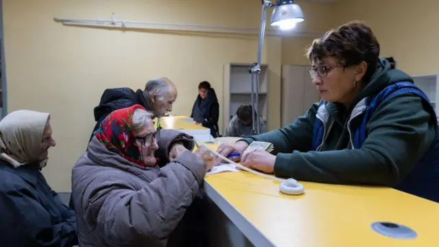 У відділенні "Укрпошти" літні жінки отримують пенсію. 