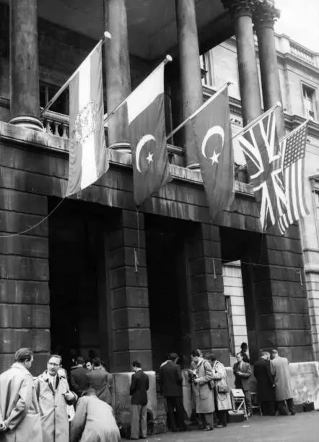 نمای بیرونی ساختمان لنسکتر هاوس لندن محل برگزاری نشست این پیمان در سال ۱۹۵۸ با پرچم کشورهای عضو پیمان بغداد و تعدادی مرد بیرون ساختمان ایستادهاند