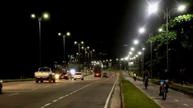 Iluminação em via pública de Belém, no Pará, com carros e ciclistas em movimento