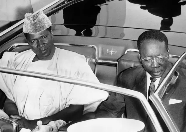 Ahmed Sekou Touré (à gauche), président de la Guinée, et Léopold Sédar Senghor, président du Sénégal (à droite), posent dans la voiture officielle, le 5 mai 1963, lors de la visite officielle de Sekou Touré à Dakar. Alors qu'il poursuivait initialement un programme socialiste, son régime s'est durci envers l'opposition et méfiant vis-à-vis de ses voisins Sénégal et Côte d'Ivoire.