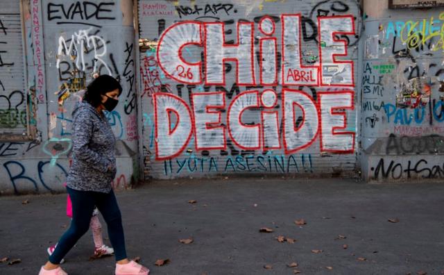 Mulher passa por uma pichação onde se lê "Chile Decide"bingo online dinheiro realreferência ao referendobingo online dinheiro real25bingo online dinheiro realoutubro para mudar a constituição da era da ditadura militar do Chile