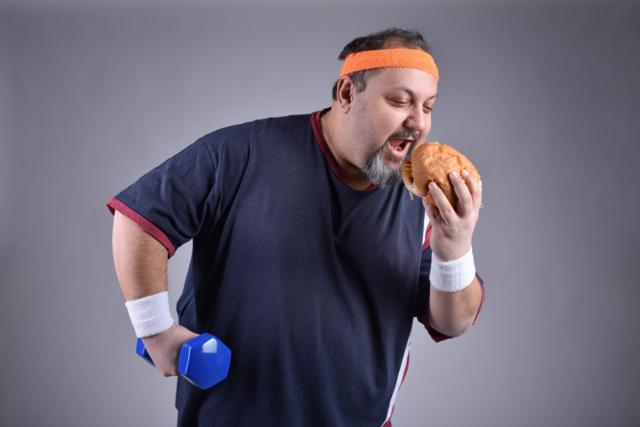 Hombre haciendo ejercicio y comiendo hamburguesa