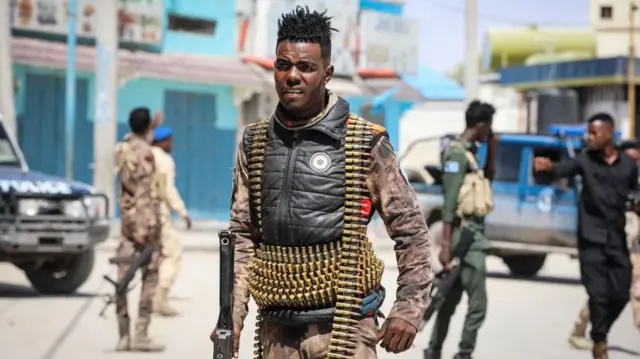 Un soldat portant une arme avec des balles autour de la taille et du cou.
