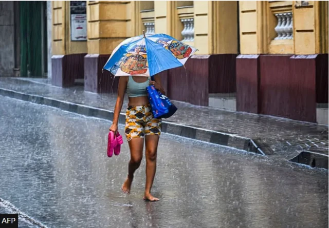 Obìnrin tó ń rìn nínú òjò ṣáájú kí ìjì líle Hurricane Melissa tó wọ ìlú Santiago de Cuba