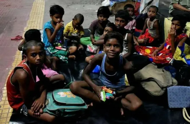 রেলওয়ে স্টেশনের প্ল্যাটফর্মে স্কুলব্যাগ নিয়ে বসে রয়েছে কয়েকজন শিশু