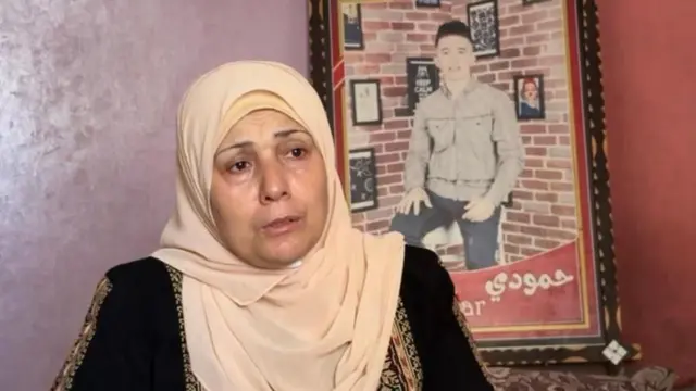 Aida al Drimli em casa, com uma foto emoldurada do filho na parede.