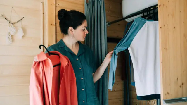 دا ښځه المارۍ ته ودرېدلې او ځانته جامې ټاکي.