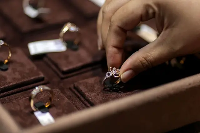 সোনার একটি আংটি আঙুলে ধরে তুলছেন একজন 