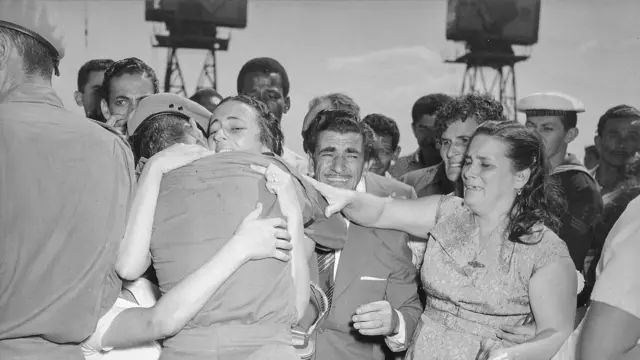 Mulher e soldado se abraçam e pessoas à volta choram durante chegada do Batalhão Suez, 1° Escalão, ao Brasil, em 21 de agosto de 1957