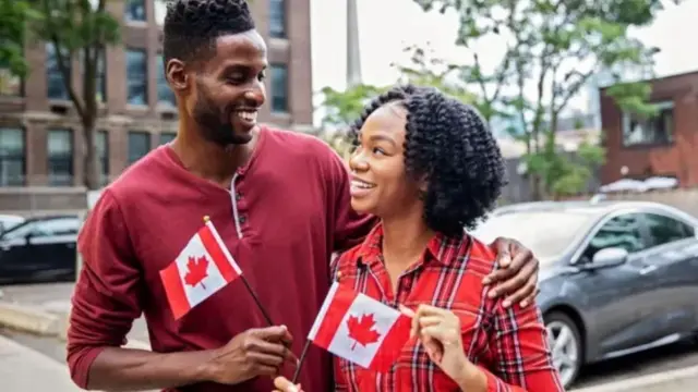 Two immigrants hold Canadian flag
