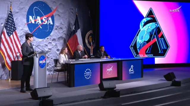 NASAや「アルテミス2」のロゴ、アメリカ国旗などを背景にした壇上で、着席して記者会見する幹部3人