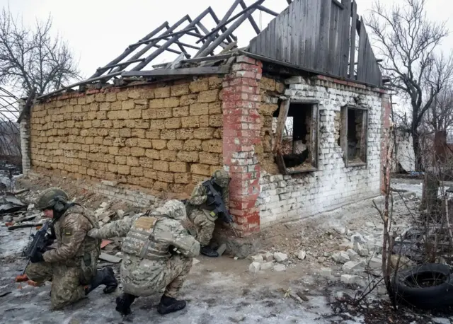 Троє солдатів ховаються біля зруйнованого будинку