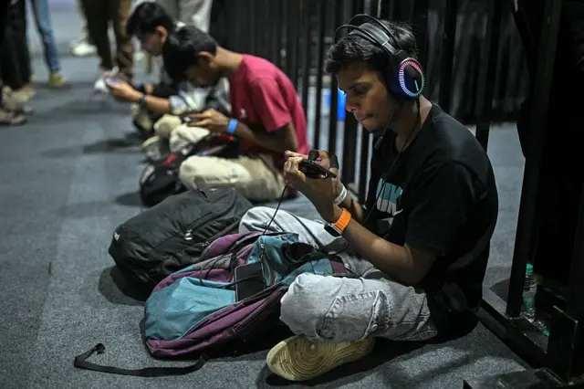 印度青年坐在地上打手游