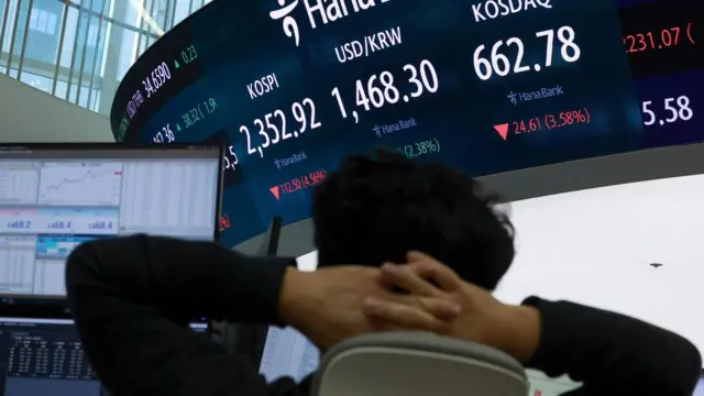 Um corretor de câmbio analisa uma tela que mostra o Índice de Preços de Ações Composto da Coreia (KOSPI) e a taxa de câmbio entre os EUA