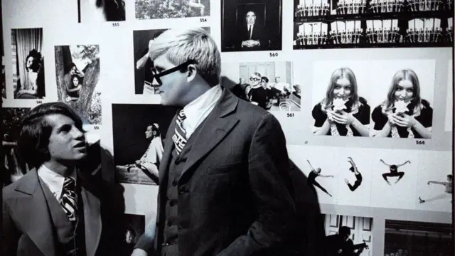 Bu Hockney ve eski erkek arkadaşının siyah beyaz fotoğrafı. Siyah beyaz fotoğraflarla çevrili bir galeride bulunuyorlar. Konuşuyorlar.