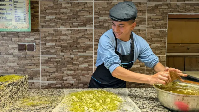 Katmer içine fıstık atan usta gülümsüyor.