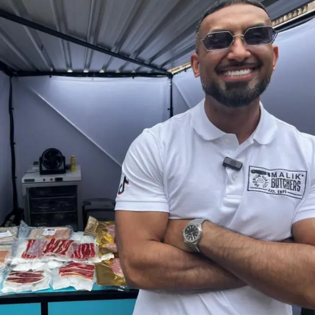Carnicero frente a una tienda con sus productos que va a vender a través de internet.