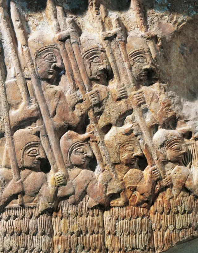 Grabado en piedra caliza mostrando soldados organizados y cargando armas