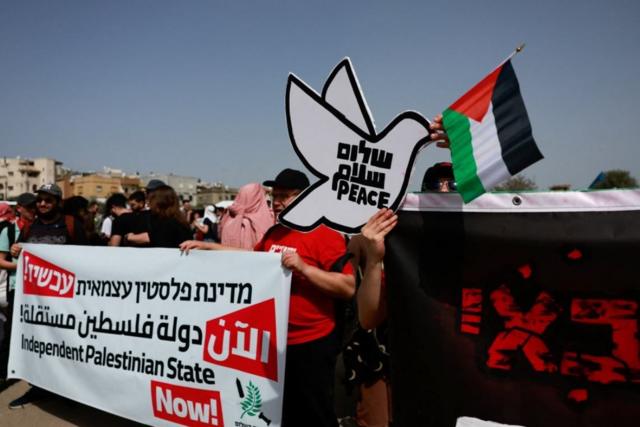 مشاركون في مسيرة يوم الأرض في الجليل يحملون يافطات تدعو للسلام وإقامة دولة فلسطينية