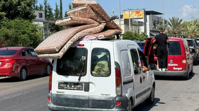 أشخاص يسافرون في سيارة محملة بالأمتعة بينما تتجه حركة المرور شمالاً من مدينة صيدا الساحلية في جنوب لبنان حيث يفر بعض اللبنانيين من القصف الإسرائيلي العنيف، لبنان 23 سبتمبر 2024.