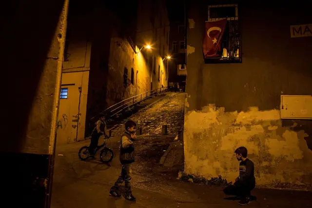 İstanbul'da akşam vakti bir ara sokakta üç tane erkek çocuk görülüyor. Biri bisiklete biniyor, diğer ikisi birbiriyle konuşuyor.