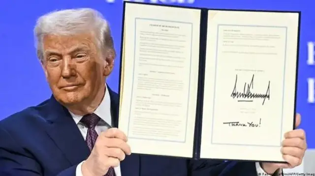 Дональд Трамп, посміхаючись, тримає у руках документ з підписом про створення Ради миру.