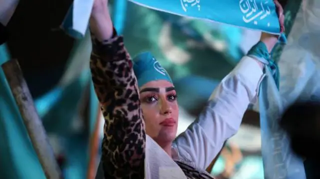 A woman supporting Pezeshkian holds up a sign at an election rally in Tehran.