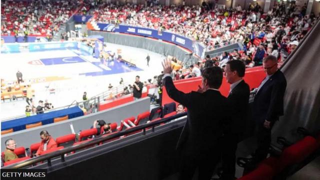 بلينكن يقف في المدرجات إلى جانب السفير الأمريكي لدى الصين والقنصل الأمريكي العام في شنغهاي حيث يتابعون مباراة في كرة السلة