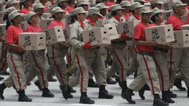 Personas con uniforme llevando cajas en Venezuela.