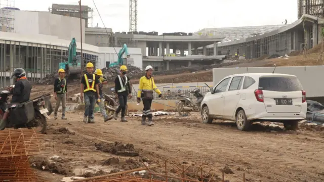 Beberapa pekerja berjalan di depan kerangka gedung Istana Negara di IKN.