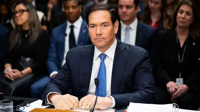 Marco Rubio masada, mikrofon başında oturuyor. 