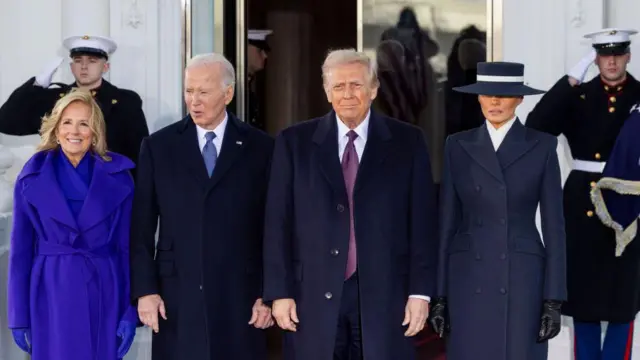 Biden ve Trump çiftleri Beyaz Saray girişinde yan yana fotoğraf çektiriyor. Jill Biden morlar içinde eşi Joe Biden ve Donald Trump siyah giyinmiş. Melanie Trump'ın lacivert giysisine lacivert bir şapka eşlik ediyor. 