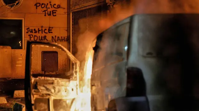 Une camionnette brûle devant un bâtiment portant des graffitis « La police tue » et « Justice pour Nahel » à Nanterre, France, un jour après l'assassinat de Nahel Merzouk, 17 ans - 28 juin 2023