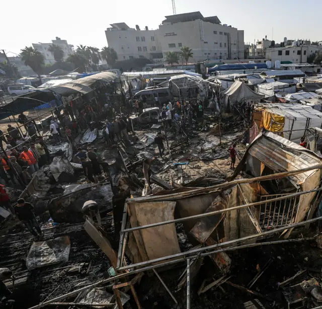 فلسطينيون يتفقدون خياماً مؤقتة مدمرة في مخيم للنازحين داخل ساحات مستشفى شهداء الأقصى، بعد غارة إسرائيلية على في دير البلح، وسط قطاع غزة، 14 أكتوبر/تشرين الأول 2024.