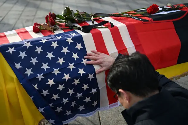 Чоловік віддає шану біля труни загиблого американського добровольця 2-го Міжнародного легіону під час церемонії прощання на Майдані Незалежності в Києві 25 листопада 2025 року