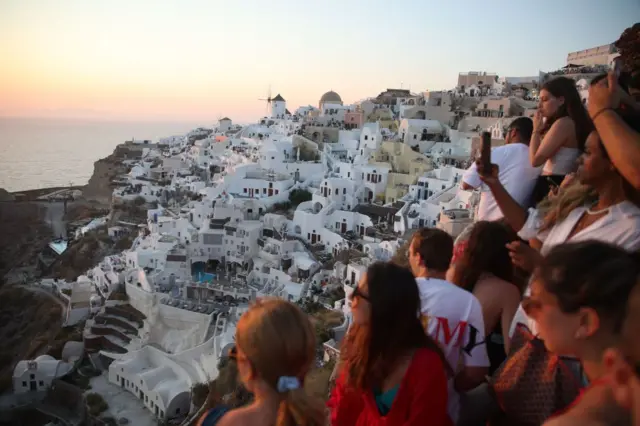 Santorini Adası'nda bir köyde etrafı izleyen turistler.