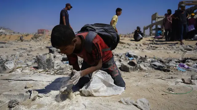 Un enfant à genoux et essaie de ramasser de la farine sur le sol à Gaza. 
