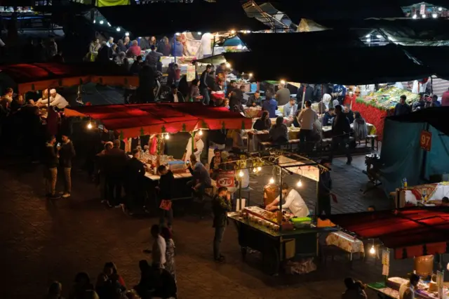 Les gens visitent les stands de nourriture sur la place Jemaa el-Fna la nuit à Marrakech.