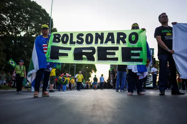 Apoiadores do ex-presidente Jair Bolsonaro, condenado pelo Supremo Tribunal Federal por liderar uma tentativa de golpe e que está em prisão domiciliar, seguram uma faixa durante um protesto pedindo anistia para os presos pelos distúrbios de 8 de janeiro de 2023, em Brasília, Brasil, em 7 de outubro de 2025.