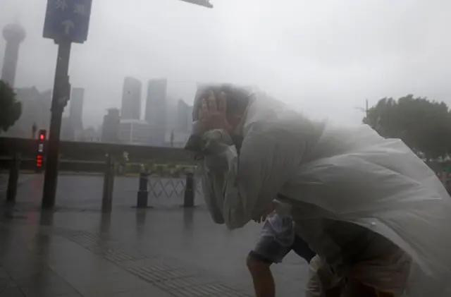 Homem se esconde do vento durante passagem do tufão Bebinca,unibet prix d ameriquesetembrounibet prix d amerique2024,