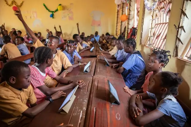 Des élèves assis sur des tables bancs dans une salle de classe à Conakry en Guinée. Ils sont initiés aux technologies numériques. 