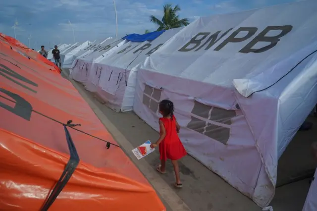 Seorang anak melintasi tenda-tenda pengungsian di Jembatan Tamiang.