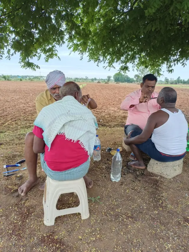 చెట్టు కింద క్షవరం చేస్తున్న క్షురకులు