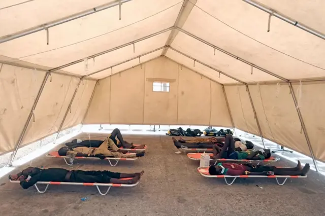 Survivants allongés sur des civières dans une grande tente