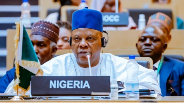 Igbakeji aarẹ Naijiria, Kashim Shettima, wọ aṣọ funfun, fila olomi aro, gbohungbohun wa niwaju rẹ